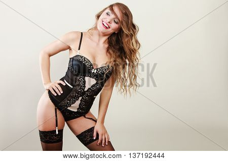 Sexuality concept. Gorgeous attractive smiling girl in black lingerie. Happy alluring woman in corset stockings and suspender belt.