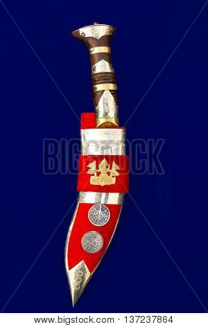 Nepali Khukuri or knife with cover on a blue background.