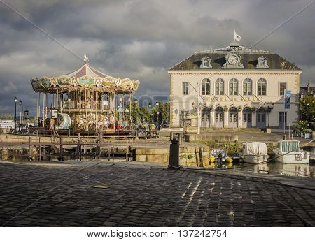 HONFLEUR HARBOUR, HONFLEUR, NORMANDY, FRANCE, 9 SEPTEMBER 2013 - Honfleur town hall and carousel in the eveing sunshine Honfleur France