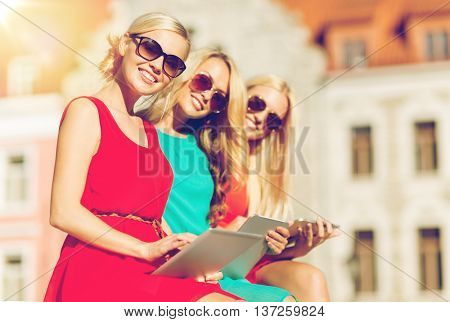 holidays and tourism concept - beautiful blonde girls toursits looking into tablet pc in the city