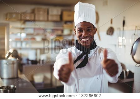 Portrait of chef standing in kitchen showing thumbs up
