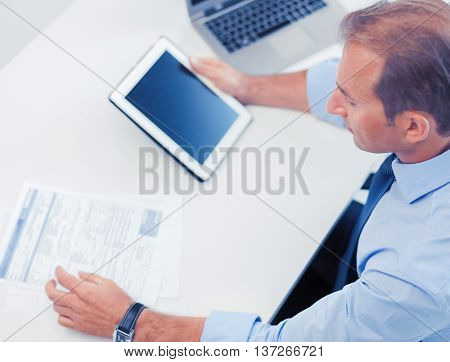 business, office, school and education concept - businessman with tablet pc and papers in office
