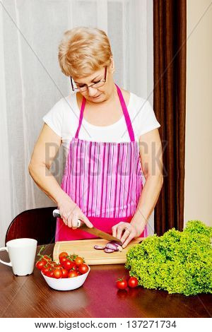 Woman cut red onion on cutting board