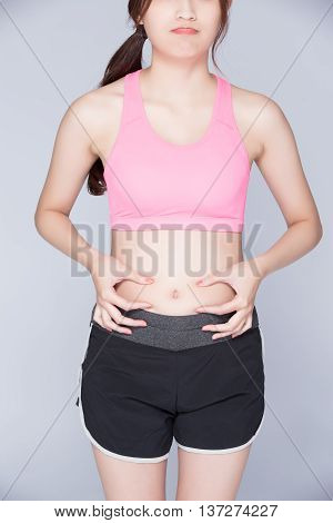 woman pinch stomach with isoltaed with gray backgroundasian