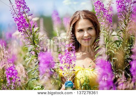 Beautiful girl on the lavender field. Young woman collects lavender