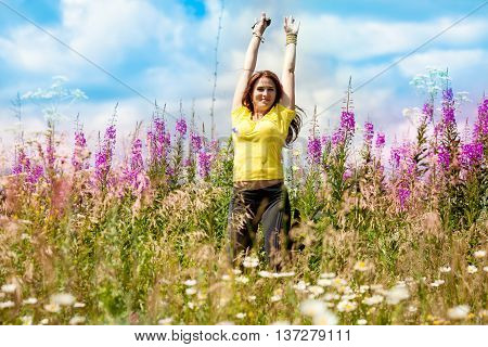 Young happy girl in the field with lilac flowers in a jump