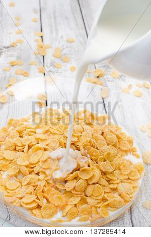 Cornflakes and milk on white wooden background. Morning breakfast. Rustic style.
