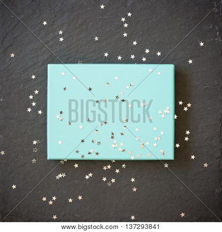 rectangular light blue box on black background with silver stars decorations. Holiday greetings. Engagement. turquoise on black board.