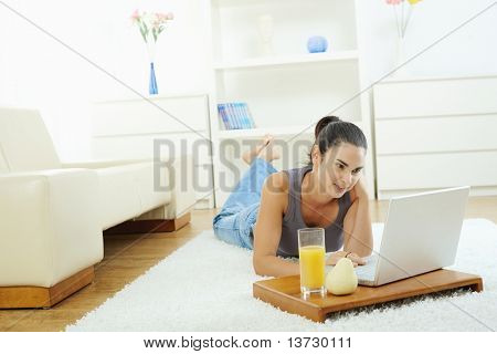 Junge Frau am Boden zu Hause liegen und arbeiten auf Laptop-Computer, Bildschirm betrachten.?