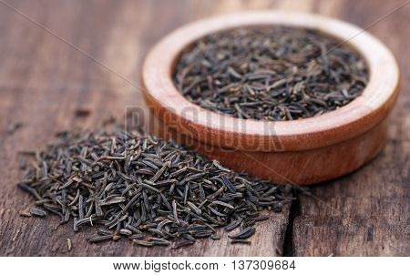 Caraway seeds in a bowl on wooden surface