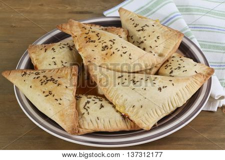 Homemade triangle pies with cheese on plate and wooden background