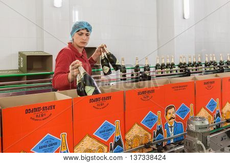 ABRAU-DURSO, RUSSIA - MAY 14, 2016: The winery Abrau-Durso. Worker puts bottles of sparkling wine in boxes.  Abrau-Durso is Russia's oldest sparkling wine producer