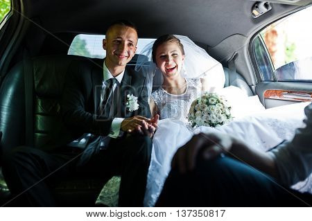 happy wedding couple sitting in limo at wedding day