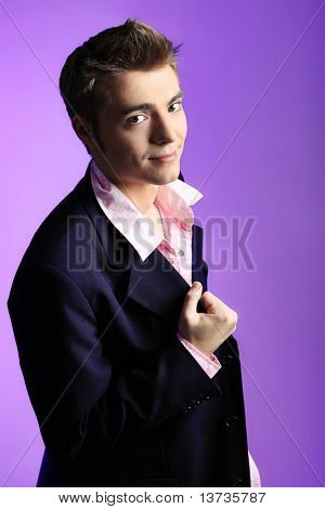 Jeune homme habillé en rock ' n ' roll style, posant sur fond bleu.