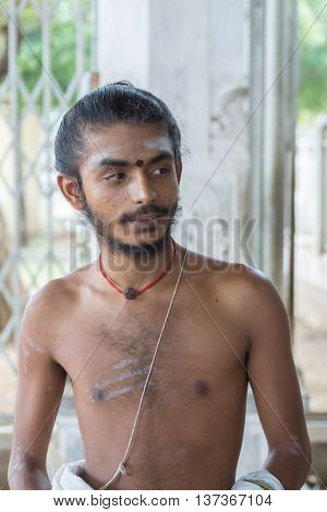 Tamil Nadu India - October 18 2013: Pillayarpatti Karpaga Vinayagar temple priest Mr. Siva Kamesh Waran is a young man with naked upper body and some white stripes on his body.