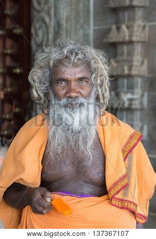 Tamil Nadu India - October 18 2013: Portrait of old priest at Pillayarpatti Karpaga Vinayagar temple a Ganesha sanctuary. He has long gray hair and long beard. Wears an ochre colored garment over his naked upper-body.