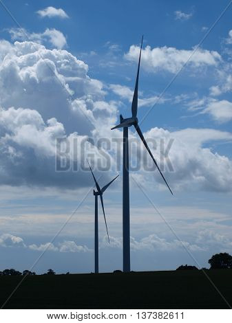 Two wind turbines against partly cloudy blue sky