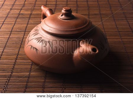 brown Chinese teapot of Yixing clay with traditional ornament on bamboo Mat