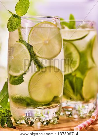 Alcohol drink. On wooden boards two glasses alcohol drink and ice cubes. A drink number forty one cocktail mohito with straw and lime and mint leaf. Country life. Outdoor. Light background.