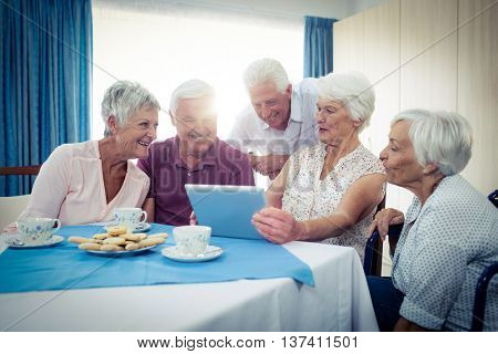 Group of seniors using a tablet computer in the retirement house