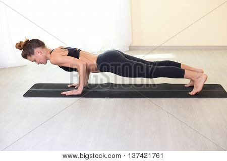 Healthy lifestyle and sports concept. sports and thin woman exercising. young adult woman doing a plank on yoga mat.