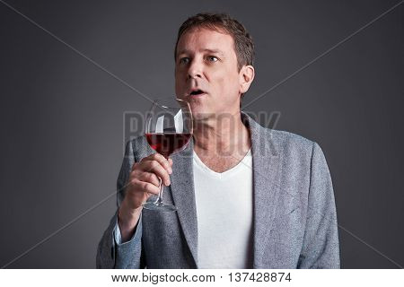A middle age man holding and smelling a glass of wine