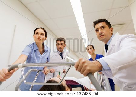 profession, people, health care, reanimation and medicine concept - group of medics or doctors carrying unconscious woman patient on hospital gurney to emergency