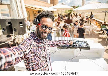 Dj taking a selfie while mixing music on a deejay set in a club people dancing