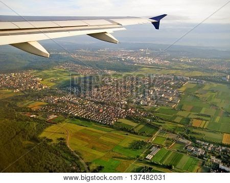 Typical german village during landing approach surrounded by fields and forest aerial view