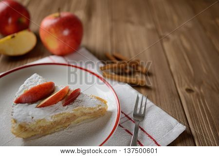 Apple pie sprinkled with sugar on a wooden background