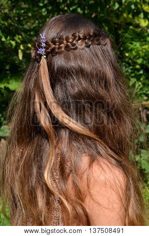 Young girl with long hair and the fine weave in the hair on the nature background