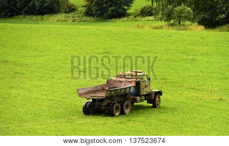 Old lorry on green meadow in summer day