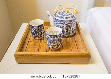 traditional white cup of tea and teapot in wooden tray closeup on table