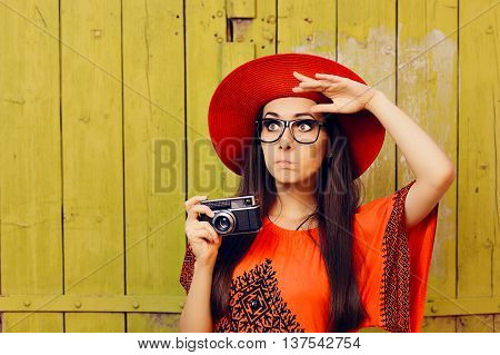 Undecided Girl with Retro Photo Camera and Red Sun Hat