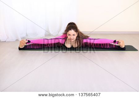 Sports lifestyle. Positive and lovely woman trains muscles flexibility. SportWoman Dressed in a beautiful colored clothing makes the splits and posing.