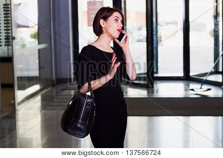 stylish and handsome woman walking and talking on mobile phone in shopping center. surprised emotions on face.