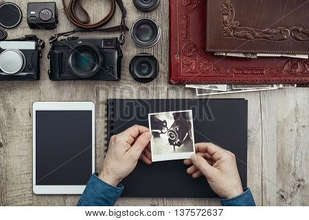 Photographic equipment digital cameras and tablet on a vintage desktop a photographer is creating his photo album