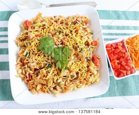 Bhel puri, an Indian popular street food, made from puffed rice and items like tomato, onion, carrot and cucumber.