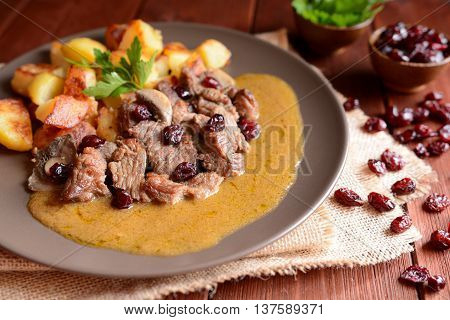 Wild boar meat with roasted potatoes, mushrooms and cranberries