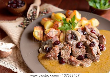 Wild boar meat with roasted potatoes, mushrooms and cranberries