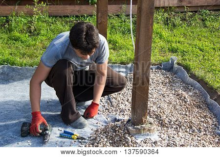 Man Fixes Electrical Cord On A Wooden Post