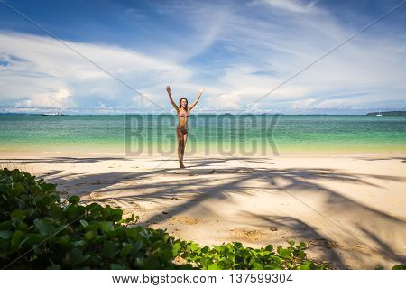 Young girl standing on the beach with her hands raised sunny summer beach holidays