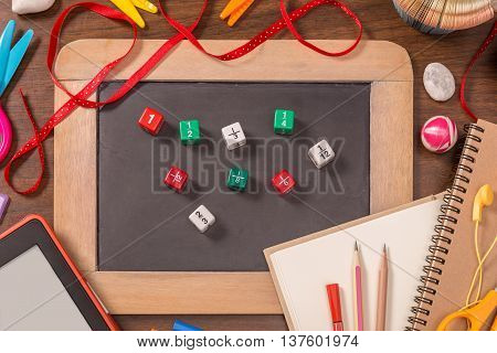 Color fraction dices on small blackboard with school supplies on wooden table