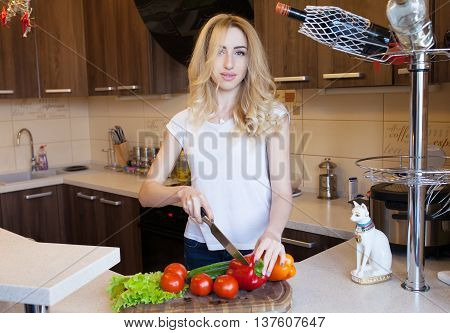 Young Happy Woman Cooking in the kitchen. Healthy Food. Dieting Concept. Healthy Lifestyle. Cooking At Home. Prepare Food. Sexy woman cutting vegetables.