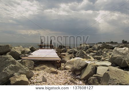 cloudy sky, path to the sea and large stones