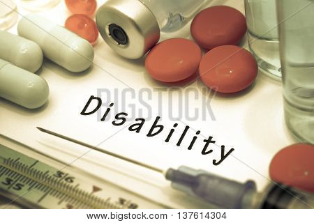 Disability - diagnosis written on a white piece of paper. Syringe and vaccine with drugs.