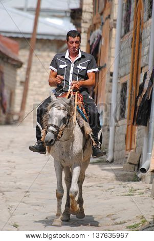 Lahic, Azerbaijan - August 30, 2014. Horse rider on the main street in Lahic mountainous village of Azerbaijan.