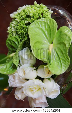 White roses and troppical leafs in a vase