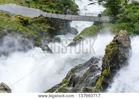 JOSTEDALSBREEN NATIONAL PARK, NORWAY - JUNE 29: Tourists go over the bridge on the way to the Briksdalsbreen glacier on June 29, 2016 in Jostedalsbreen National Park, Norway. 