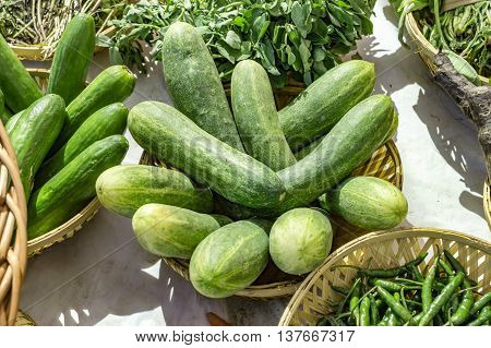Green cucumbers and other vegetable items on sale.